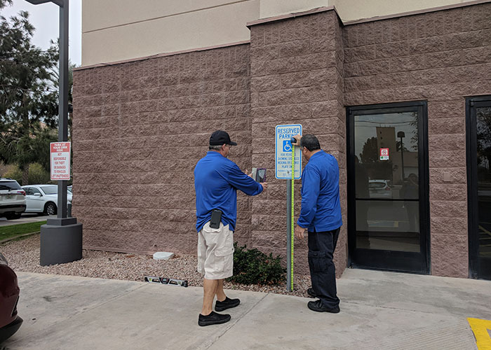 Two Life Quest team members measuring the height of a sign designating accessibility