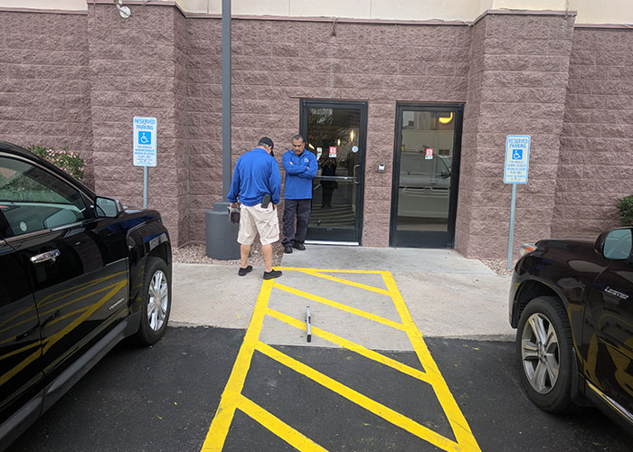 Two Life Quest team members measuring the slope of a parking space access aisle