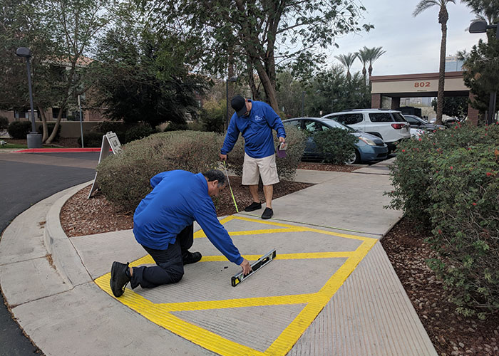 Two Life Quest team members measuring the slope of a curb ramp