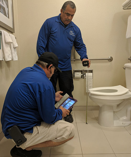 Two Life Quest team members measuring toilet seat height