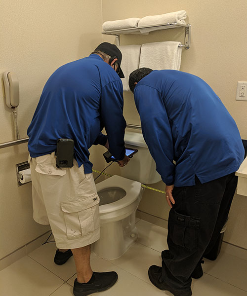 Two Life Quest team members measuring toilet center line from side wall