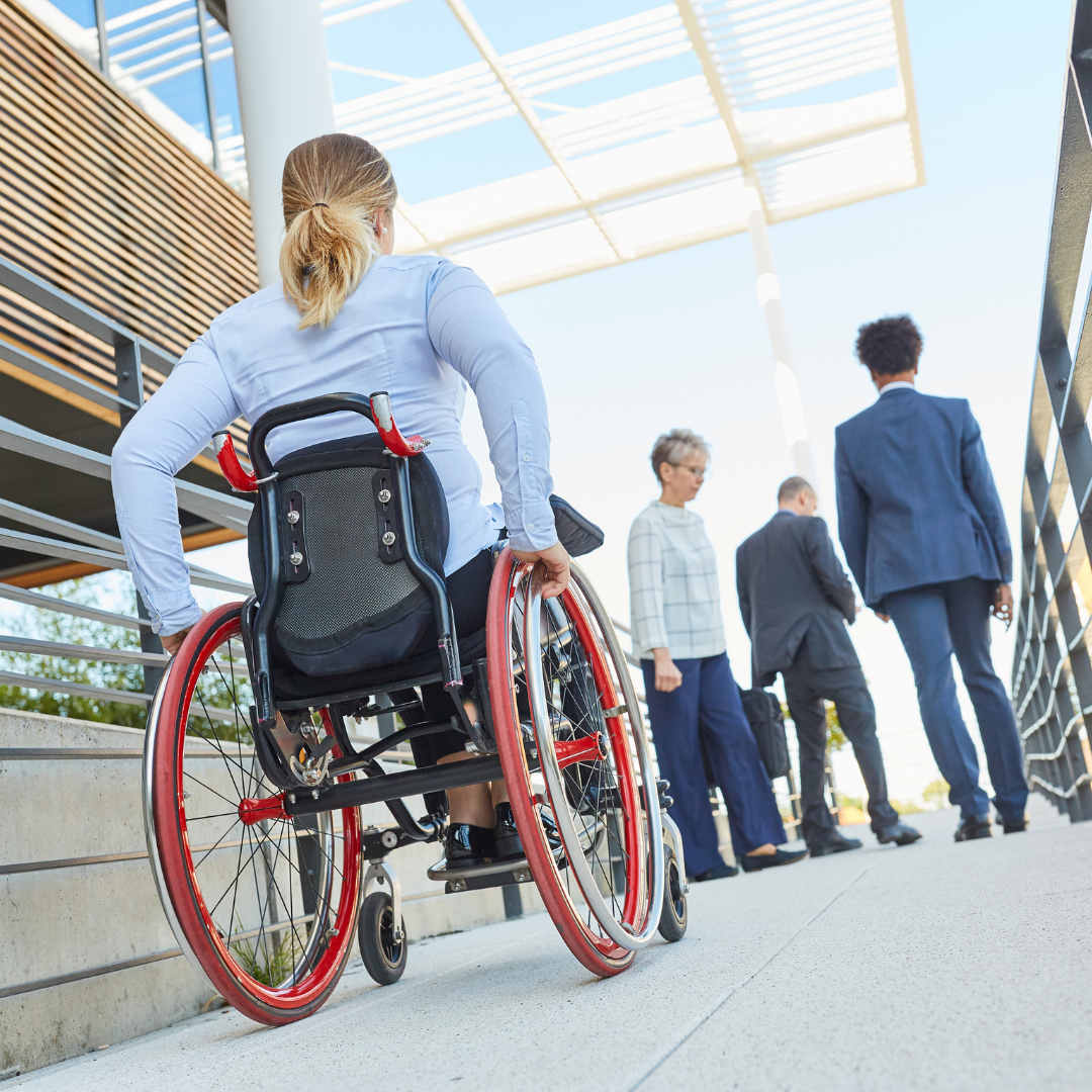 A wheelchair user approaching 3 of her colleagues.
